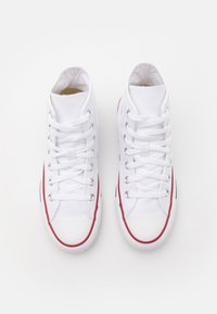 Weiße High-Top-Sneaker mit Textil-Obermaterial, Gummisohle und roten Akzenten an den Seiten. Sie verfügen über Schnürsenkel und eine minimale Ausstattung auf der Zunge.