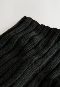Schwarzer Strickstoff mit einer gerippten Textur, der abwechselnd erhabene und vertiefte Muster aufweist und ein wellenförmiges Erscheinungsbild erzeugt.