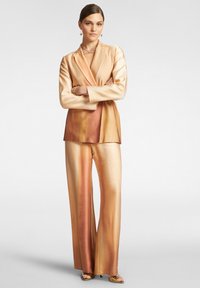 Completo in satin composto da giacca avvolgente a maniche lunghe in tonalità di oro chiaro e pantaloni a gamba larga con una sfumatura di delicati toni arancioni.