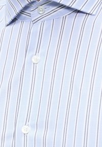 Chemise bleu clair à rayures verticales gris foncé et clair, boutons blancs et col classique.