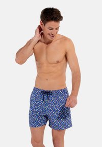 Shorts de bain bleus avec un motif abstrait coloré, taille à cordon de serrage et tissu léger, conçus pour le confort et la liberté de mouvement.