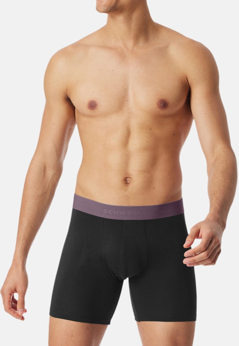 Schwarze Boxershorts mit einem violetten Bund, der das "SCHIESSER"-Logo trägt, aus einem glatten, dehnbaren Material für Komfort und Passform.