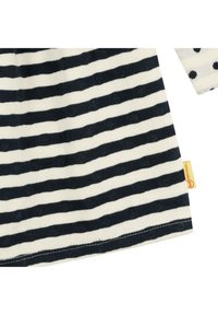 Indumento a maniche lunghe a righe in blu navy e crema, con un motivo testurizzato e un'etichetta sull'orlo. Presenta pois su una manica.