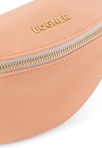 Borsa di colore pesca realizzata in tessuto strutturato con un design curvo. Presenta una cerniera dorata con un'apertura fluida e un logo impresso sul davanti.