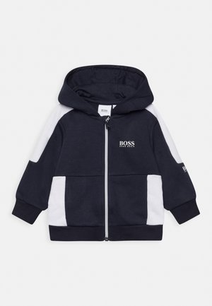 Donkerblauwe en witte hoodie voor peuters met ritssluiting, voorzakken, lange mouwen, capuchon en het "BOSS HUGO BOSS" logo op de borst en mouw.