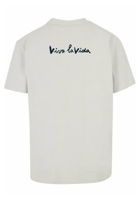 Lys grå bomulds t-shirt med korte ærmer og rund halsudskæring. Har teksten "Viva la Vida" i mørkeblå kursiv på ryggen.