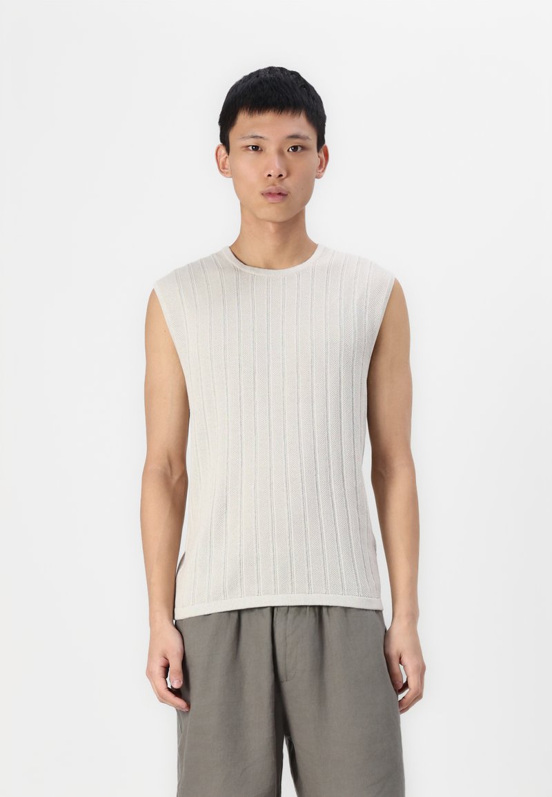 Un haut tricoté sans manches gris clair avec une texture à côtes verticales, un col rond et une coupe décontractée. Associé à un short gris ample.