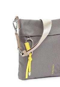 Borsa in tessuto intrecciato grigio e bianco con una tracolla gialla, dettagli in metallo argentato e pelle beige. Design regolabile e versatile.
