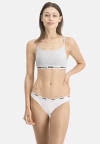 Brassière de sport en coton gris avec des bretelles réglables et une bande logo noire. String en coton blanc avec une ceinture logo noire. Design simple et fonctionnel.