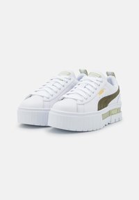 Vita sneakers med en tjock vit sula, grå detaljer och ett grönt streck. Har texturerat paneler och framträdande varumärkesdetaljer.