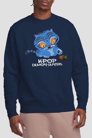 Navy sweatshirt with cartoon blue tiger with large yellow eyes tipping over a small plant pot, text "KPOP DEMON HUNTERS" below.