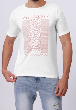 Homme portant une chemise blanche à manches courtes avec un motif de vague rouge et un texte japonais faisant référence à la pochette de l'album Unknown Pleasures de Joy Division.