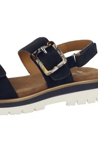 Námořnické modré semišové sandály s širokým páskem, dekorativní sponou ve tvaru želvoviny a polstrovanou hnědou stélkou, se širokou bílou podrážkou.