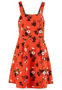 Robe rouge sans manches à larges bretelles, taille cintrée, avec un motif floral noir, blanc et jaune sur l'ensemble.