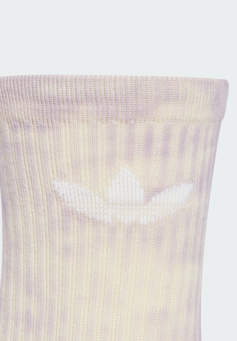 Jasnolawendowe i kremowe skarpety w prążki z białym logo trefoil blisko góry. Miękka tekstura, typowa dla materiałów bawełnianych.