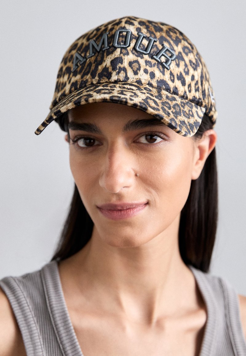 Leopardenmuster-Cap mit flachem Schirm, versehen mit dem Wort "AMOUR" in fetten schwarzen Buchstaben. Sanfte Textur, überwiegend in Braun- und Schwarztönen.