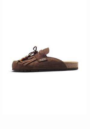 Zapato tipo slip-on de ante marrón con flecos y detalles de cuentas, suela de corcho y base de goma plana, mostrado de perfil sobre fondo blanco.