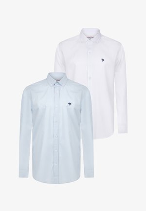 Zwei langärmlige Hemden mit Knöpfen: eines in Himmelblau und eines in Weiß, beide mit einem kleinen marineblauen Vogel-Logo auf der linken Brust und Standardkragen.
