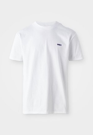 Bela kratka majica s kratkimi rokavi in krožnim ovratnikom, z majhnim črnim logotipom "OBEY" na zgornji levi strani prsnega koša, položena na belo podlago.