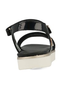 Zwarte gepatineerde leren sandaal met een dikke witte zool, voorzien van twee verstelbare banden en subtiele gouden accenten op het beslag. Vlakke, getextureerde inlegzool.
