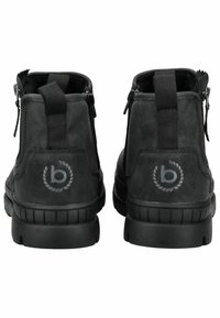 Botines negros de cuero hasta el tobillo, con cremalleras a ambos lados, suelas de goma texturizadas y un detalle de logo en la parte trasera.
