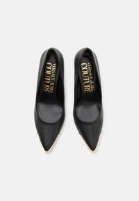 Escarpins en cuir noir à bout pointu, avec un accent doré à la pointe, un intérieur de marque et une texture lisse.