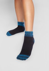 Mustad mustamat ja sinised pahkluusokid, millel on tekstuuriline disain: soliidne must keha ning sinised, mustrit sisaldavad äärised ja varbad.