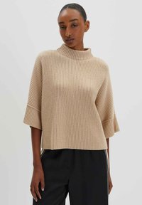 Beige gestrickter Pullover mit hohem Kragen, kurzen Ärmeln und gerippter Textur. Der Stoff wirkt weich und bequem.