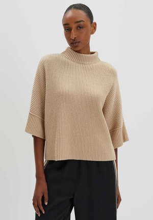 Beige knitted sweater with a high collar, short sleeves, and ribbed texture. The fabric appears soft and comfortable.