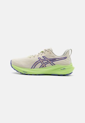 Light beige running shoe with purple accents and a textured upper. Features a green midsole and blue outsole for traction and support.