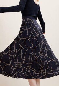 Jupe marine avec plis, présentant un motif géométrique beige. Le design est ample et fluide, avec une texture lisse et une taille ajustée.