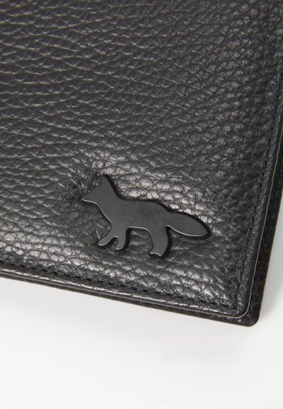 Portefeuille en cuir noir avec une surface texturée, orné d'un logo de renard noir dans le coin inférieur, contrastant avec la texture du matériau.