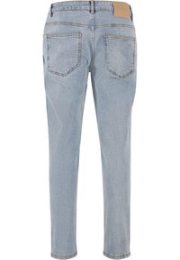 Lyseblå denimjeans vist bakfra med to lommer og en lys brun lærlapp på midjebåndet.