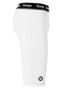 Weiße Sportshorts mit einem schwarzen elastischen Bund und "Kempa"-Markenlogo, glatter Textur, knielangem Design und Logodetail an der unteren Seite.