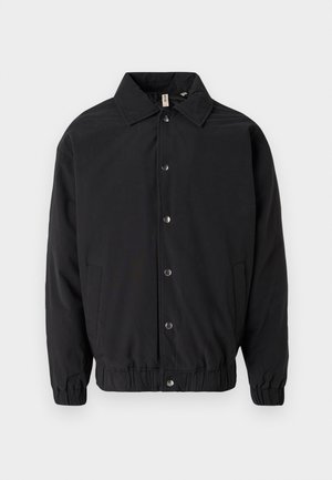 Zwarte jas met een kraag, drukknopen aan de voorkant, elastische manchetten en zijzakken. Gladde stof met een eenvoudig ontwerp.