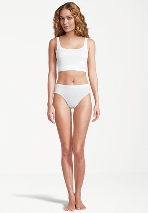 Weißer Baumwoll-Bralette mit quadratischem Ausschnitt und elastischem Band; kombiniert mit weißen hochgeschnittenen Panties. Glatte Textur, ohne Muster.