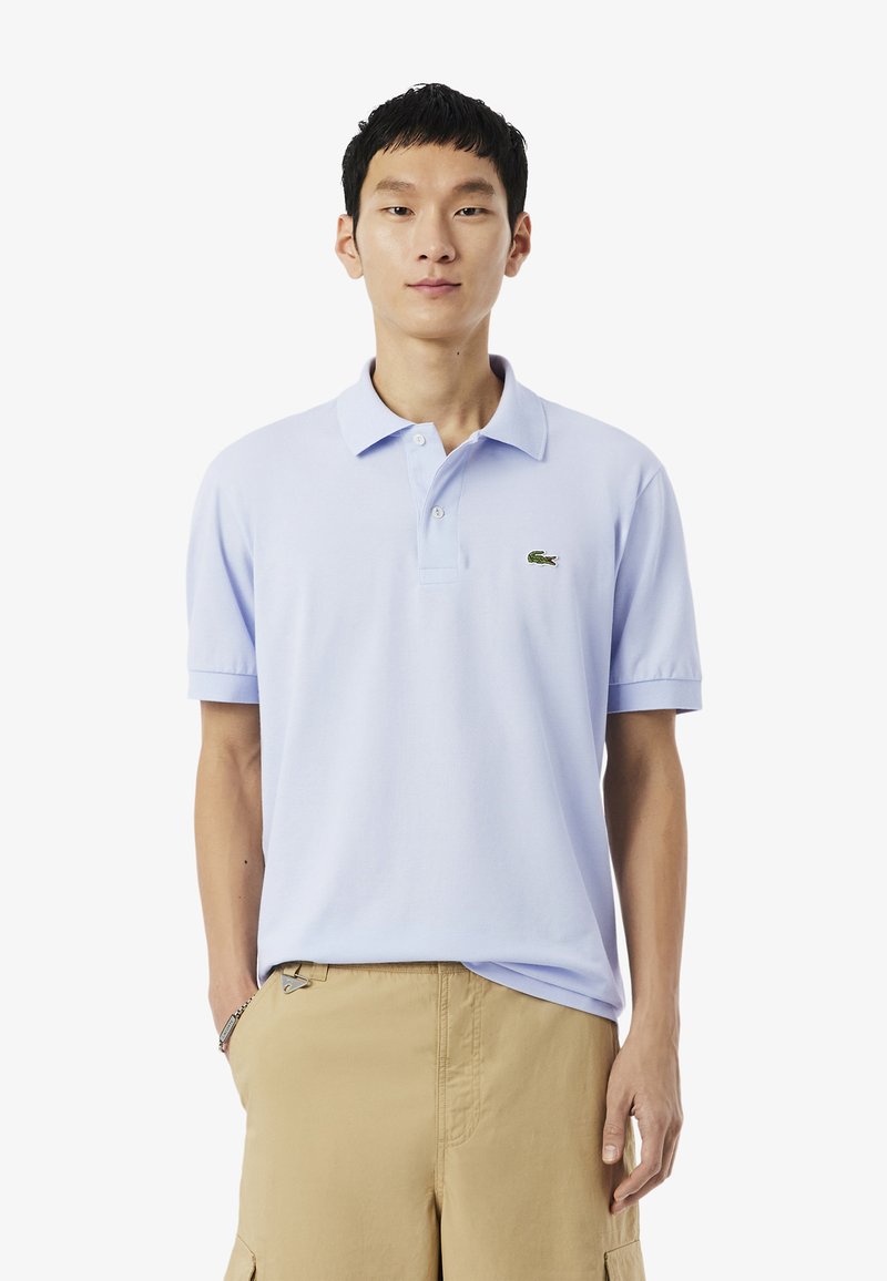 Lichtblauw poloshirt van katoen, met een klassieke kraag, korte mouwen en een klein groen logo op de borst.