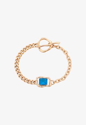 Zlatý náramek s obdélníkovým modrým kamenem, texturovaným designem článků a otevíracím sponou pro zapínání.