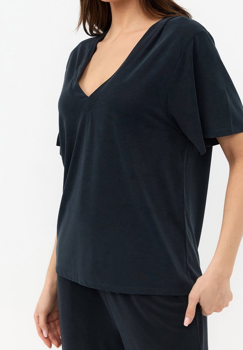 Maglietta V-neck a maniche corte blu scuro, realizzata in tessuto morbido. Vestibilità leggermente ampia con orlo regolare, che mette in mostra una texture liscia.