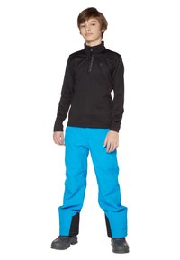 Schwarzer Fleece-Pullover mit Reißverschlusskragen und blauen wasserdichten Hosen mit schwarzen Knöchelbündchen, kombiniert mit dunklen Stiefeln. Glattes Material, funktionales Design.