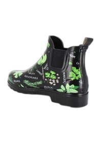 Zwarte rubberen enkellaars met groene kruidencgraphics, met een ronde neus, elastische zijpanelen en een gestructureerde zwarte zool voor grip.