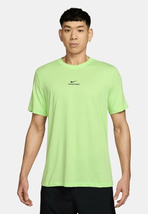 Hombre vistiendo una camiseta de manga corta Nike Pro color lima y pantalones cortos negros, de frente contra un fondo liso.