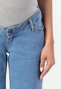 Jeans in denim azzurro chiaro con un design classico a cinque tasche, dotati di chiusura con bottone e leggeri segni di usura sulle cuciture.