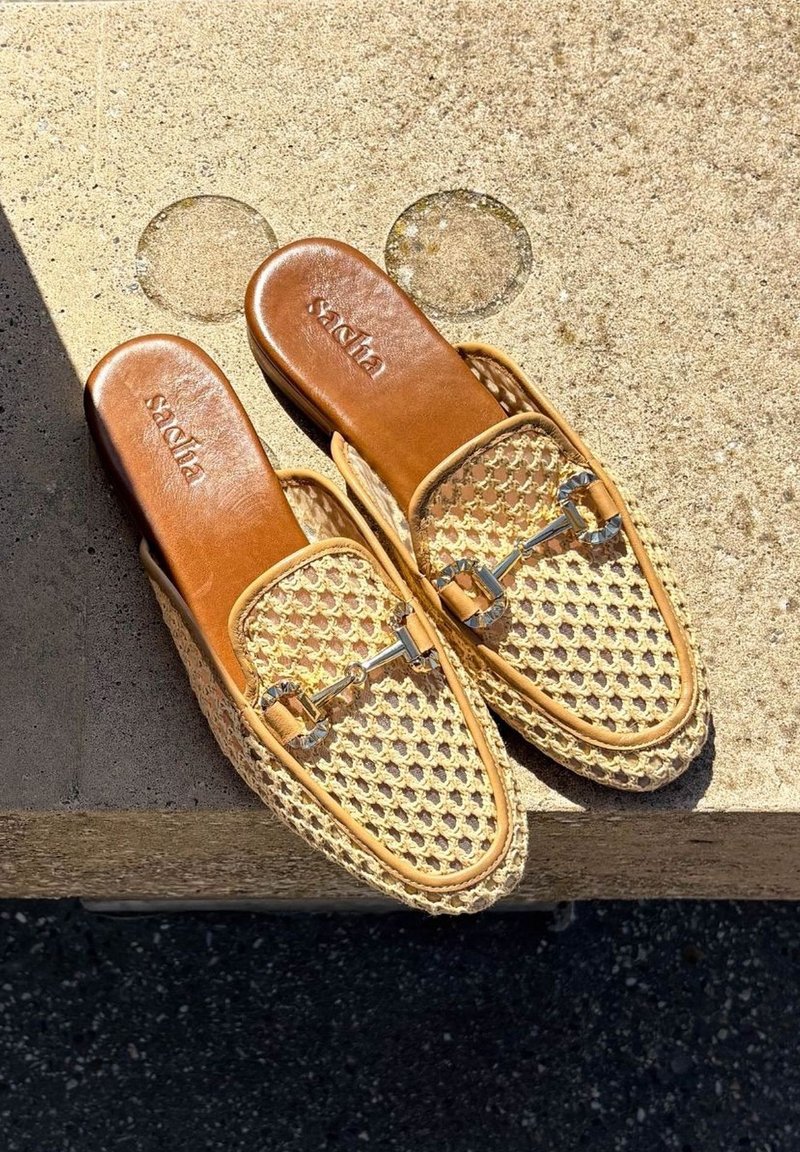 Beige geweven instap-schoenen met leren accenten en metalen hardware, met een mandachtige textuur en een afgeronde neusontwerp.