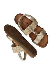 Une paire de sandales beiges avec des sangles métalliques et des bandages élastiques à l'arrière, des semelles texturées et un détail décoratif doré sur les sangles supérieures.