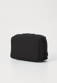 Black zippered pouch with a soft, textured exterior. Rectangular shape with rounded edges, featuring a subtle seam detail along the sides.