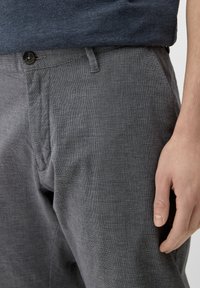 Grå byxor i lätt tyg med en strukturerad mönstring, slät front och en enda knappstängning med sidfickor.