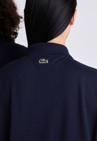 Námornícky polo tričko s golierom, na zadnej strane s malým zeleným vyšitým logom krokodíla. Hladký bavlnený materiál.