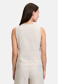 Top sans manches en lin beige avec des rayures verticales blanches. Coupe droite avec un encolure arrondie et sans fermetures. Texture douce.