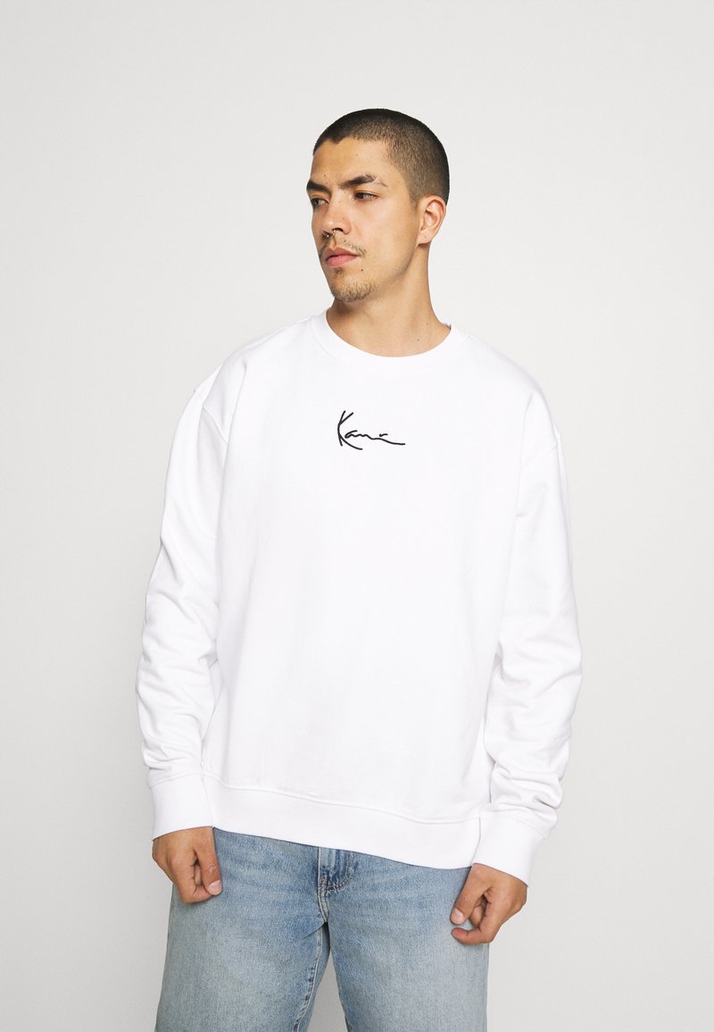 Witte sweatshirt met een ronde hals en lange mouwen, voorzien van een zwart handgeschreven logo op de borst. Draag het met lichtblauwe jeans.